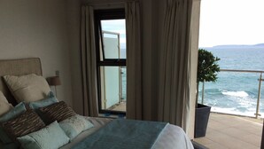 Et soveværelse med seng, et vindue med gardiner, havudsigt og en balkon med gelænder.