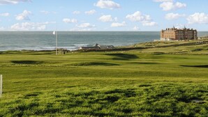 A coastal golf course with a large building in the background.