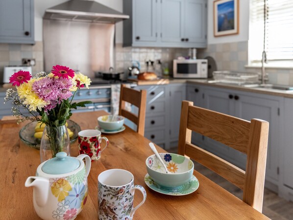 A kitchen with a wooden table, a vase of flowers, and various kitchenware. - 2 bedroom accommodation in Totland Bay (Totland Bay)
