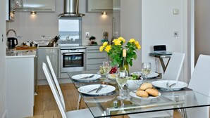 Une cuisine moderne avec un coin repas, des appareils électroménagers en acier inoxydable et une vue sur la mer.