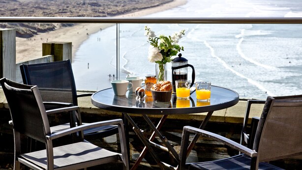 Un balcon avec une table préparée pour le petit-déjeuner, donnant sur une plage.