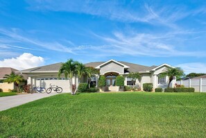A two-story house with a garage, a well-maintained lawn, and a clear blue sky.
