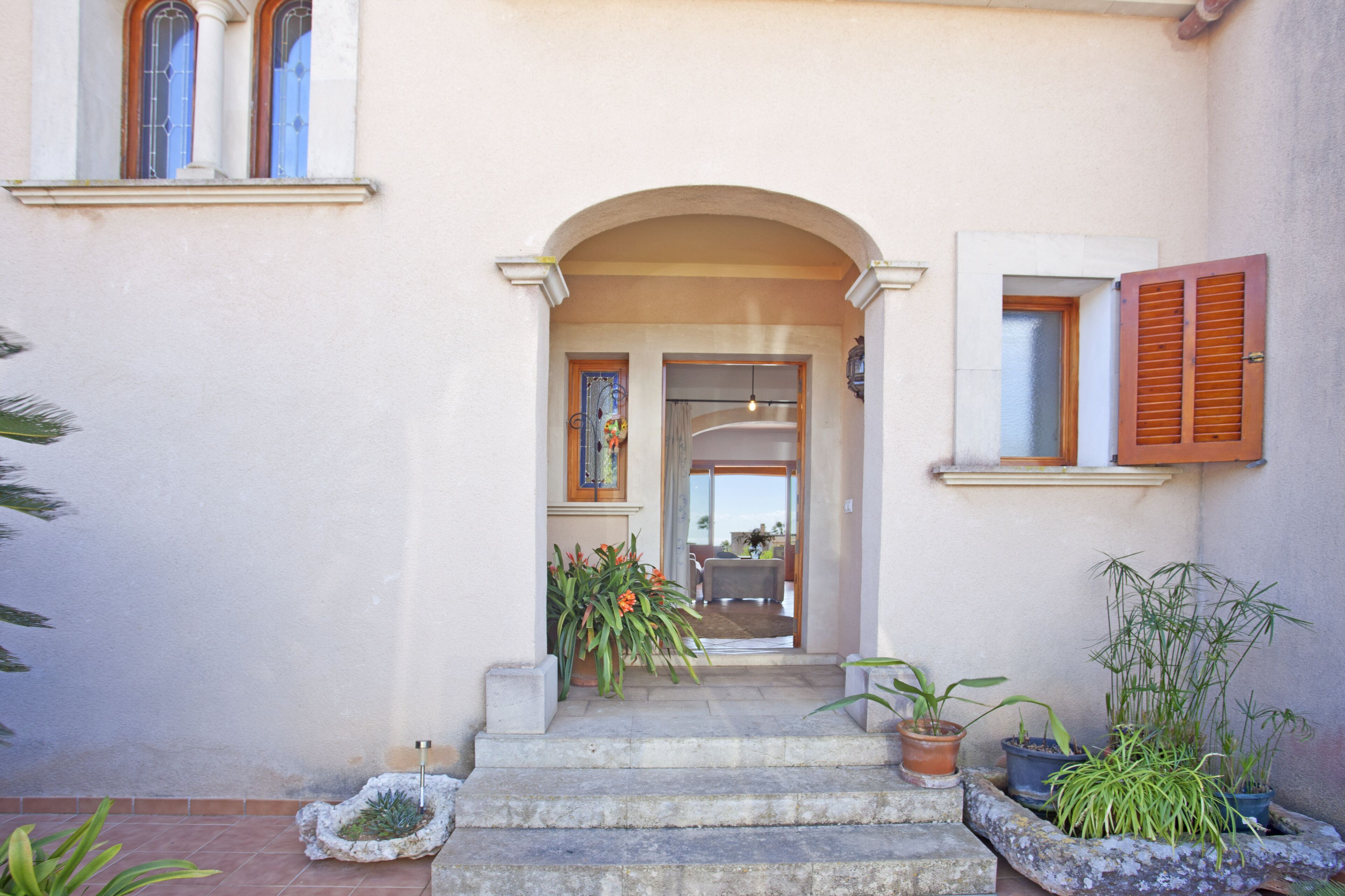 A building entrance with a stone staircase, potted plants, and a door leading to an interior space.