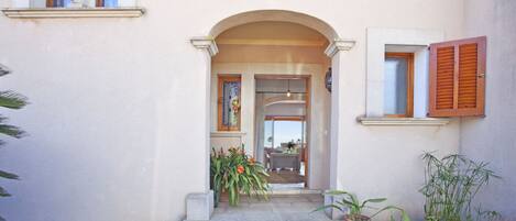 A building entrance with a stone staircase, potted plants, and a door leading to an interior space.