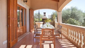 A covered outdoor dining area with wooden furniture and a view of the garden. - Finca with sea views and pool special offer last week of August (Calonge)