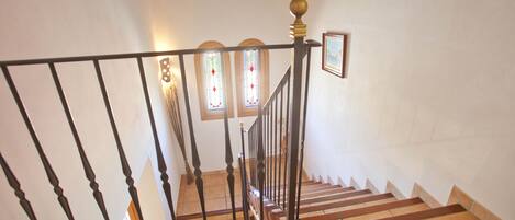 Un escalier avec une rampe noire, des marches en bois et un sol carrelé.