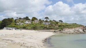 A coastal area with a sandy beach, a rocky shoreline, and houses on a hillside. - 1 bedroom accommodation in Falmouth (Falmouth)