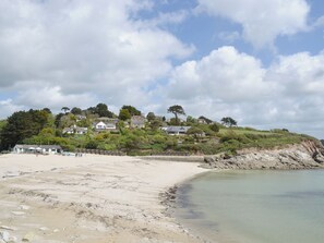 Una zona costera con una playa de arena, un litoral rocoso y casas en una ladera.