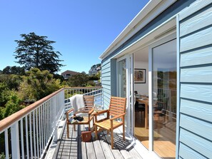 A wooden deck with a glass door leading to an interior dining area.