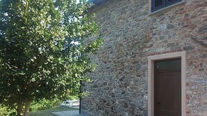 A stone building with a wooden door, a paved pathway, and a tree in front. - CA GIACOMO, in the middle of the Lunigiana woods .. relax ... and unique atmospheres (Serrapiana)