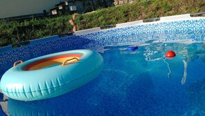 A swimming pool with clear blue water, a blue inflatable ring, and a red floating ball. - CA GIACOMO, in the middle of the Lunigiana woods .. relax ... and unique atmospheres (Serrapiana)