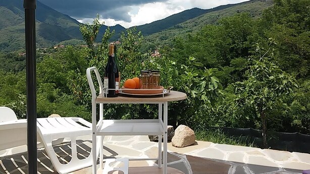 A table with a bottle and fruits on a terrace with a mountain view. - CA GIACOMO, in the middle of the Lunigiana woods .. relax ... and unique atmospheres (Serrapiana)