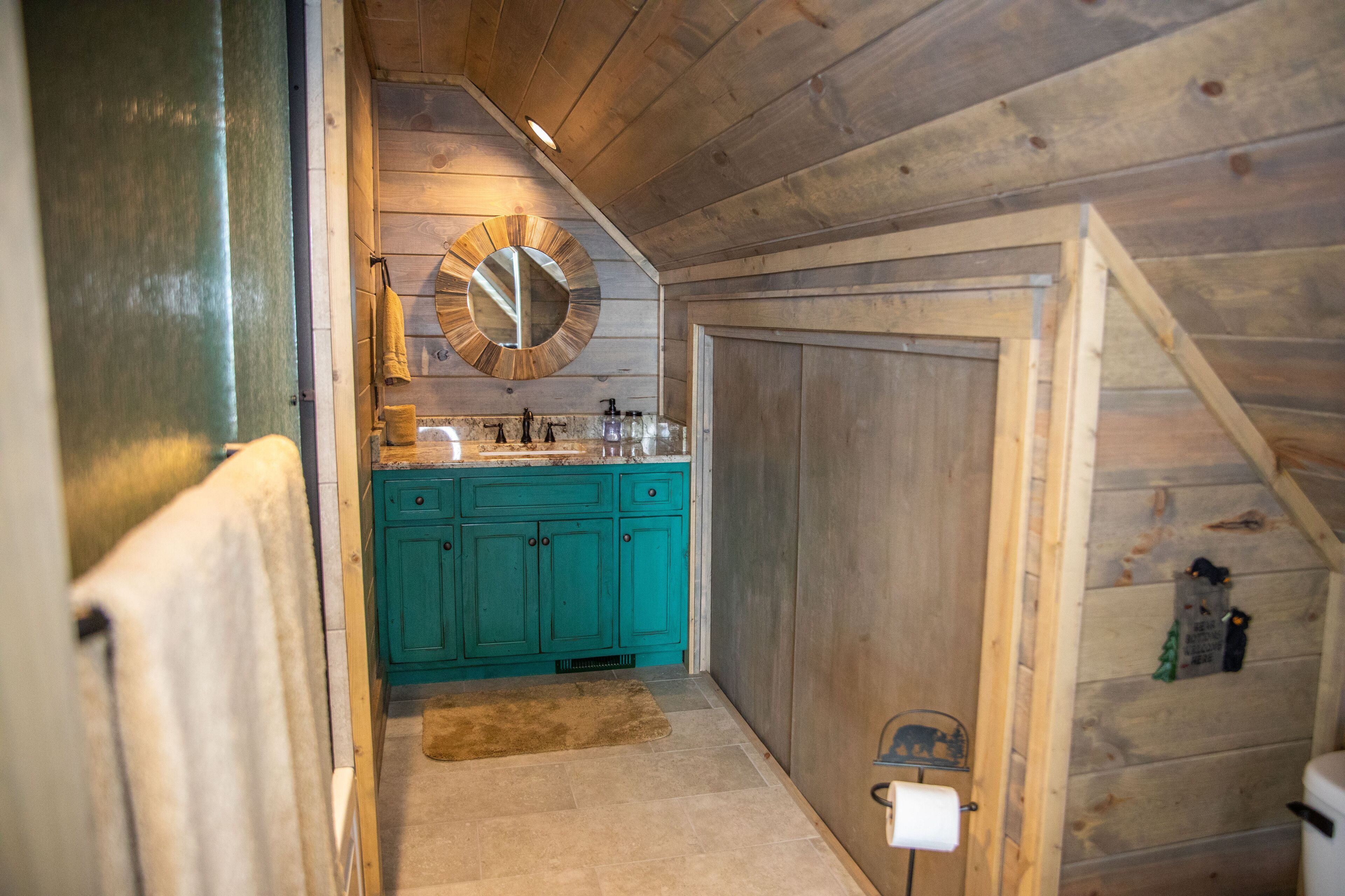Ein Badezimmer einer Holzhütte mit Waschbecken, Spiegel und Schränken.