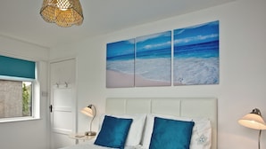 A bedroom with a bed, two bedside lamps, a window, and a wall-mounted artwork. - Trevistas, Padstow, Cornwall (Padstow)
