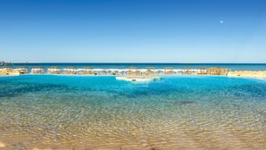Un complexe hôtelier doté d’une piscine, de chaises longues et offrant une vue sur la mer.