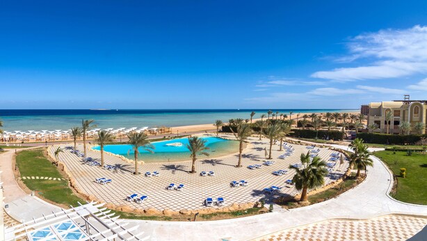 Un complexe hôtelier doté d’une piscine, d’une plage et de palmiers.