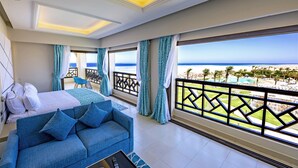 Une chambre d’hôtel avec un balcon, un lit, un canapé bleu et une vue sur la plage.