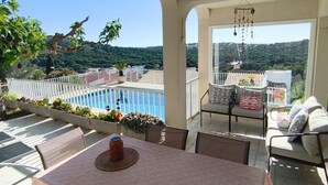 Un balcón con piscina, mobiliario exterior y vistas del paisaje.