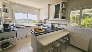 Una cocina moderna con armarios blancos, encimera negra y vistas al exterior.