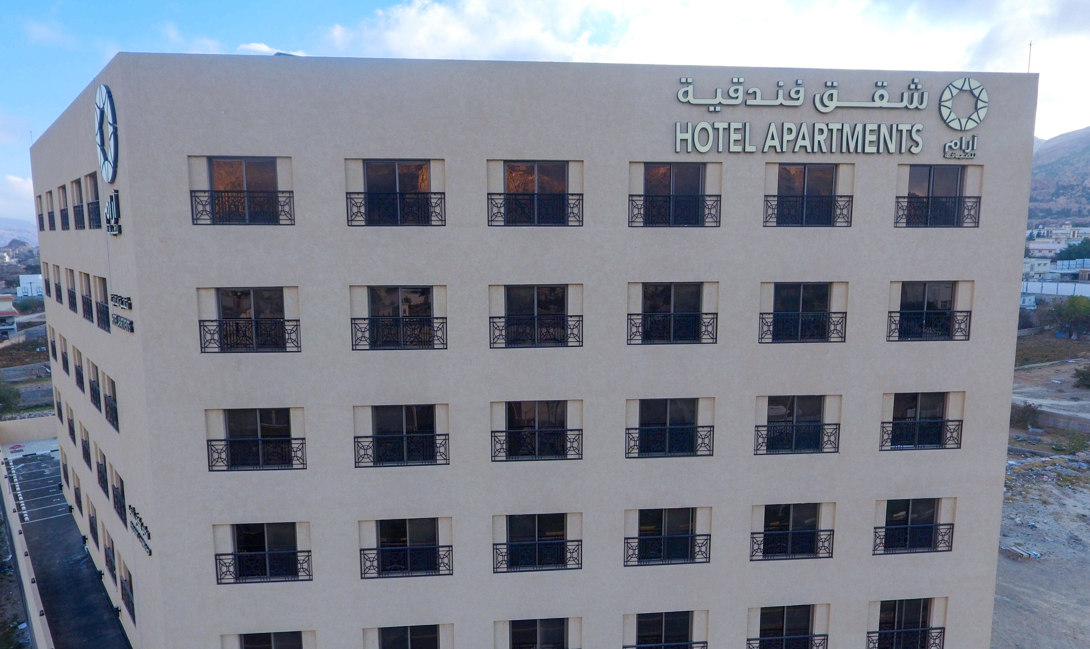 A multi-story hotel building with balconies and a clock on the facade.