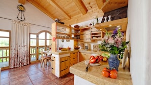A kitchen with wooden cabinets, a dining area with chairs, and a large window with curtains.