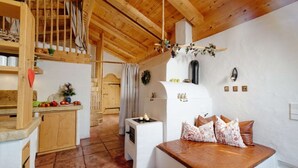 A cozy kitchen with wooden beams, a white stove, and a bench with cushions.