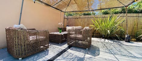 Un patio al aire libre con mobiliario de mimbre, una mesa y un toldo.