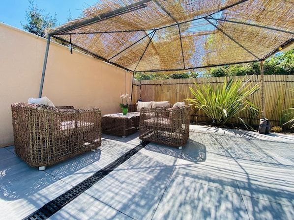 An outdoor patio with wicker furniture, a table, and a canopy. - Gite du golf with swimming pool (Montauban)