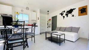Ein modernes Wohnzimmer mit einem weißen Sofa, einem Couchtisch und einem Essbereich mit Tisch und Stühlen.