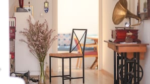 A room with a wooden floor, a chair, a table with a gramophone, and a staircase. - Moshinos Otel (Ayvalik)