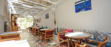 A cafe with wooden tables and chairs, a patterned floor, and a ceiling with a unique design.