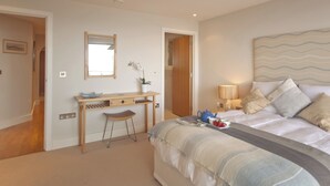 Ein Schlafzimmer mit Bett, Nachttisch, Lampe und Schreibtisch mit Stuhl.