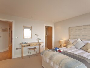 A bedroom with a bed, bedside table, lamp, and a desk with a chair. - 3 bedroom accommodation in Westward Ho! (Westward Ho!)
