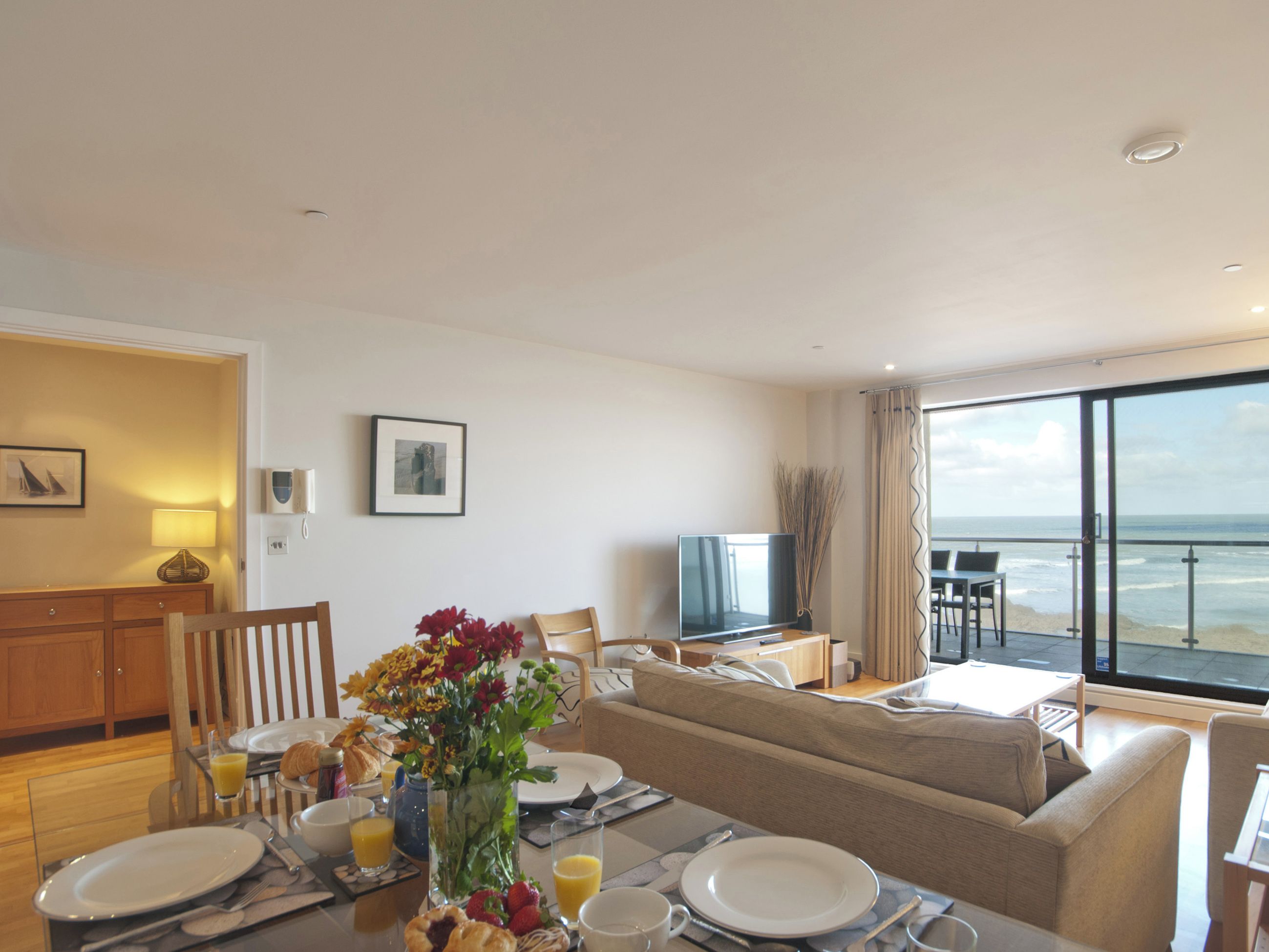 Un coin repas avec une table mise pour le petit-déjeuner, un canapé et une vue sur l’océan.