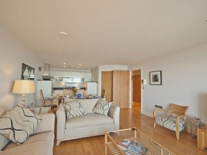 A living room with a sofa, a coffee table, and a dining area with chairs and a table. - 3 bedroom accommodation in Westward Ho! (Westward Ho!)