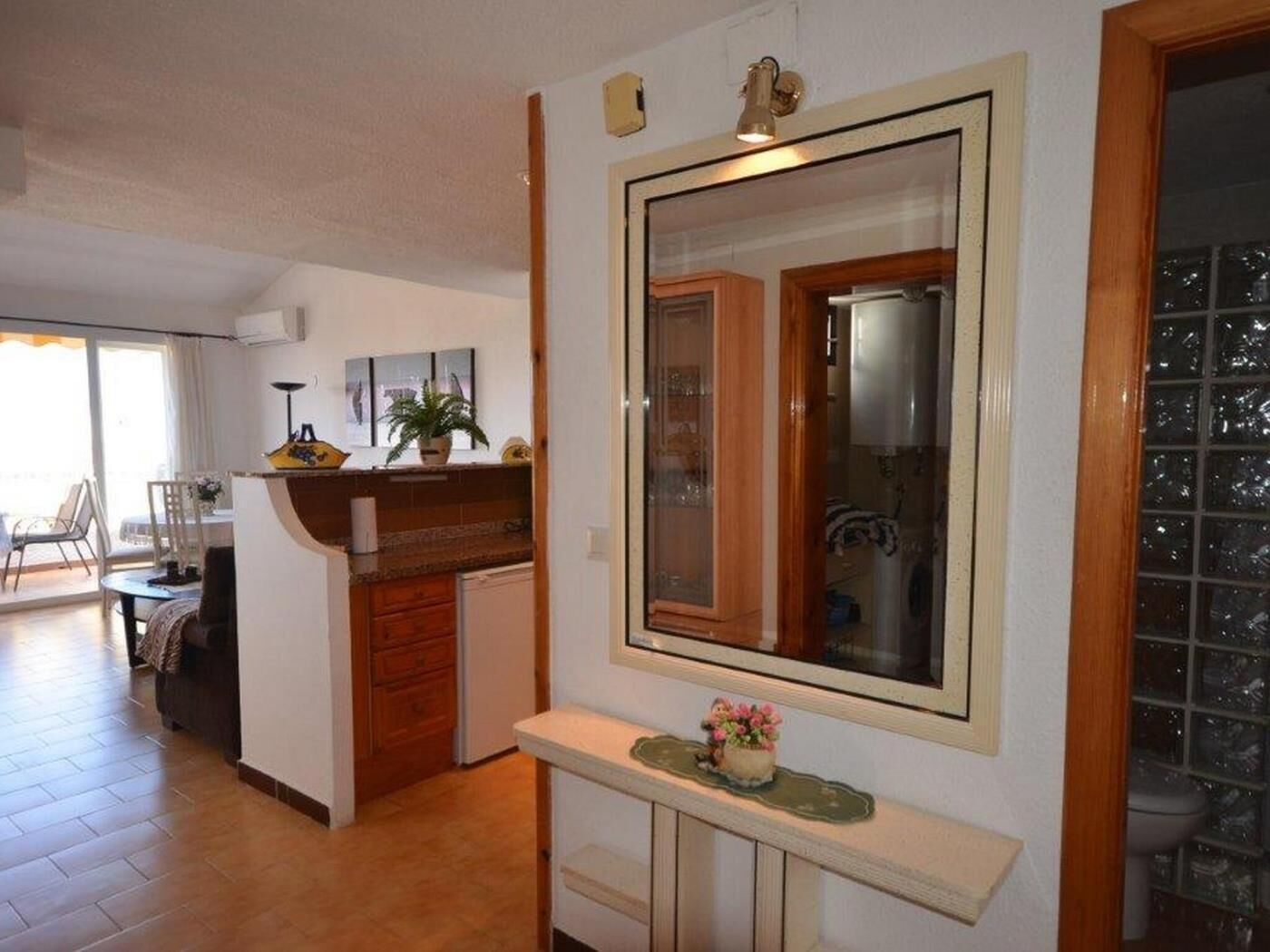 A kitchen with a wooden cabinet, a countertop, and a mirror.