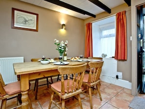 A dining area with a wooden table, chairs, a vase of flowers, and a framed map on the wall.