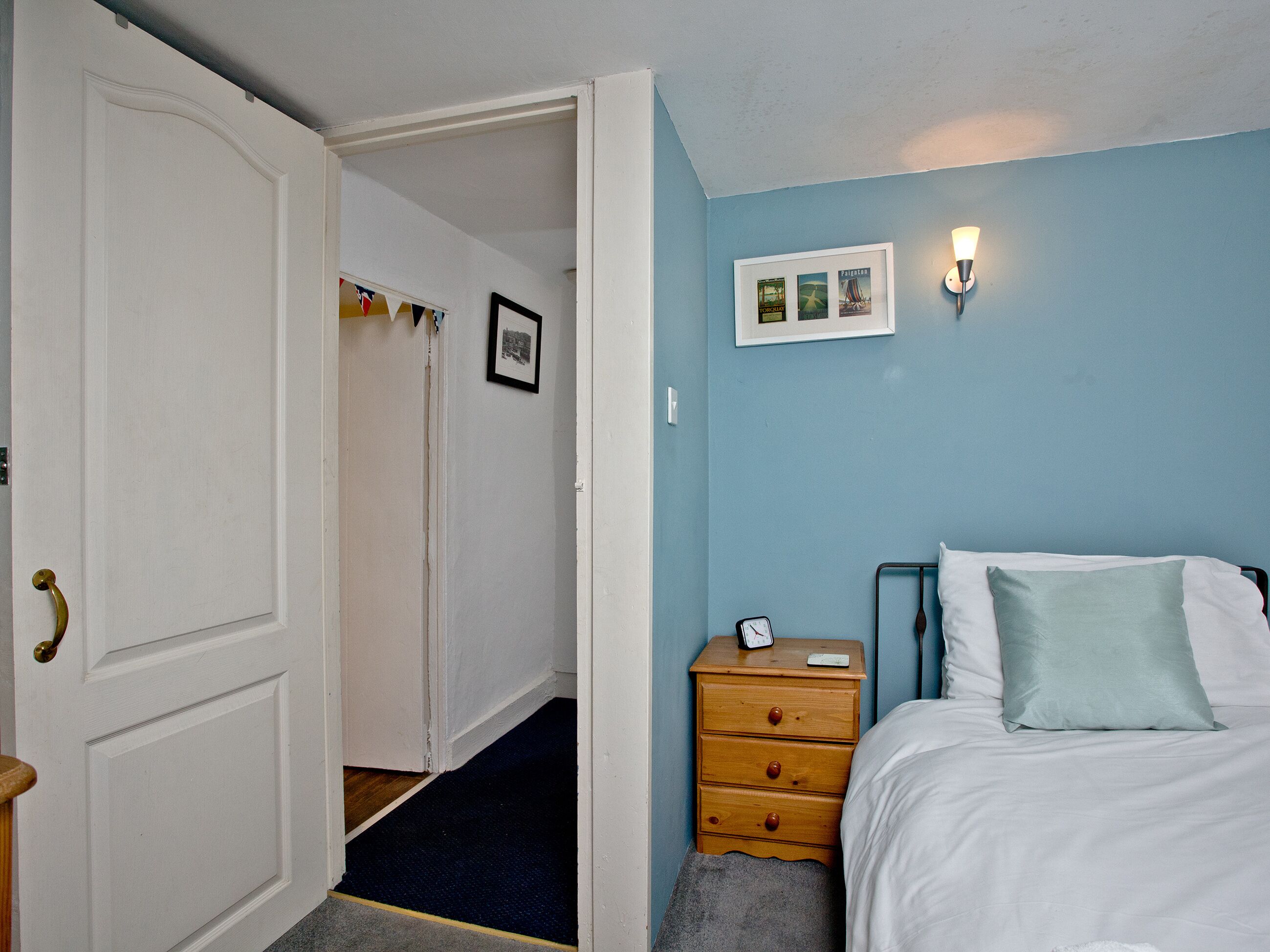 A bedroom with a bed, a dresser, and a nightstand. There is a door leading to another room.