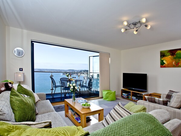 A modern living room with a large window overlooking a scenic view, a flat-screen TV, and a cozy seating area.