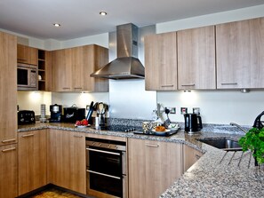 A modern kitchen with wooden cabinets, stainless steel appliances, granite countertops, and a built-in oven.