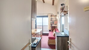 Un espacio habitable compacto con kitchenette, comedor y sofá.