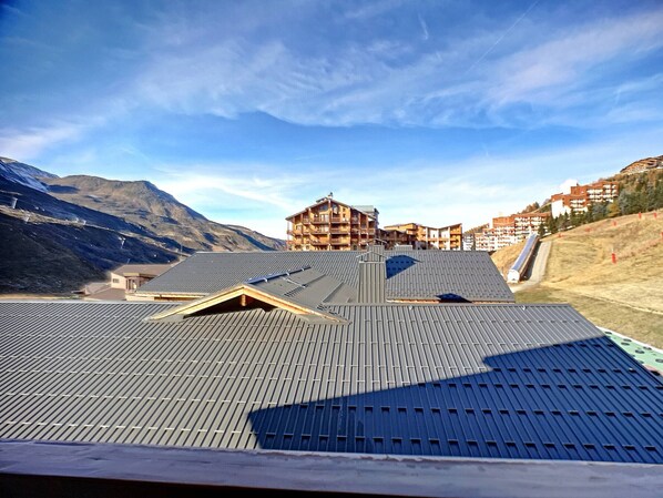 A hotel with a sloped roof, multiple balconies, and a mountainous backdrop.