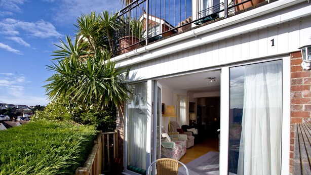 A balcony with a table, chairs, and a potted plant. - A spacious apartment overlooking Goodrington Park with sea views. (Paignton)