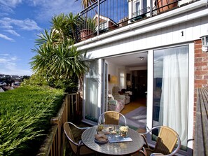 Un balcon avec une table, des chaises et un pot de fleurs.