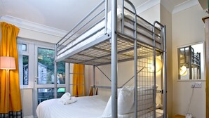 A bunk bed room with a window, a lamp, a bedside table, and a mirror. - A spacious apartment overlooking Goodrington Park with sea views. (Paignton)