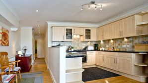 A modern kitchen with light wood cabinets, a central island, and a dark countertop. - A spacious apartment overlooking Goodrington Park with sea views. (Paignton)