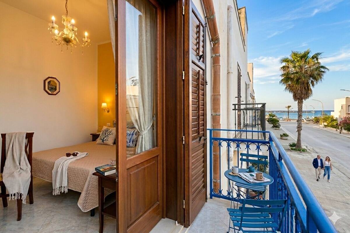 A balcony with a table and chairs, a bed with a view, and a railing.