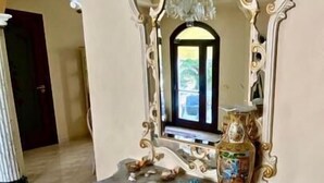 A grand mirror with ornate gold and white frame, placed on a marble-topped console table with decorative items. - Araba Fenice (San Vito Lo Capo)