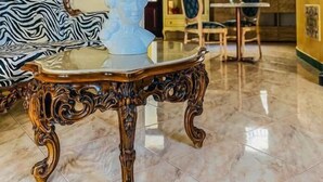 A room with a marble floor, a white vase with purple flowers, a zebra-patterned sofa, and a wooden table with intricate carvings. - Araba Fenice (San Vito Lo Capo)