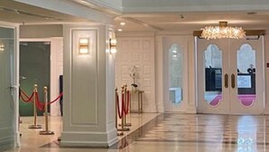 Un hall d’entrée spacieux, doté d’un plafond haut, d’un lustre imposant et d’un grand tableau abstrait.
